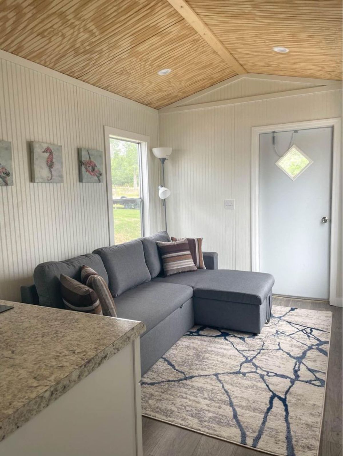 Living area of Brand New 35’ Tiny House has a soft L shaped couch