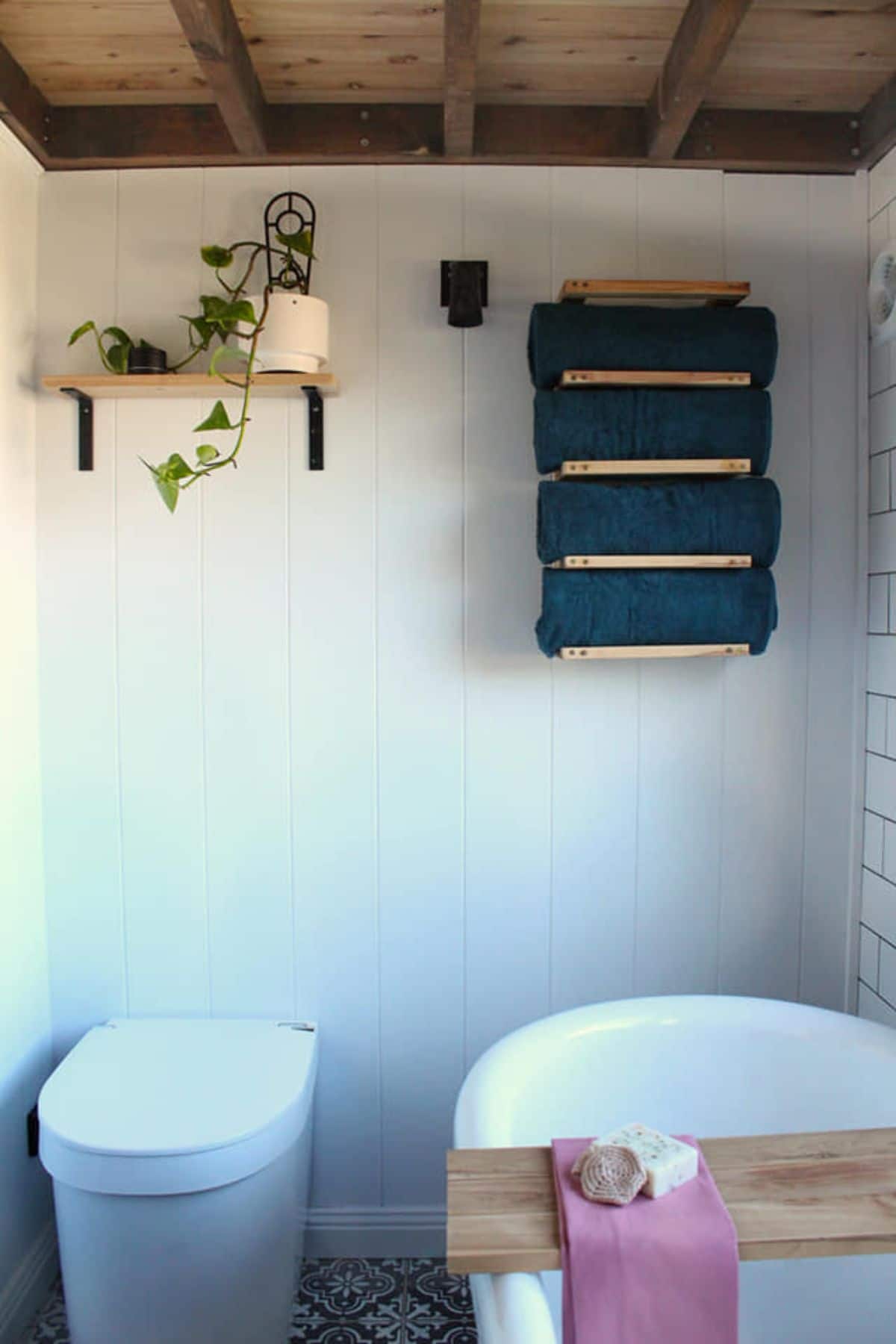 Bathroom of Handbuilt Modern Tiny Farmhouse has a standard toilet and wooden rack behind