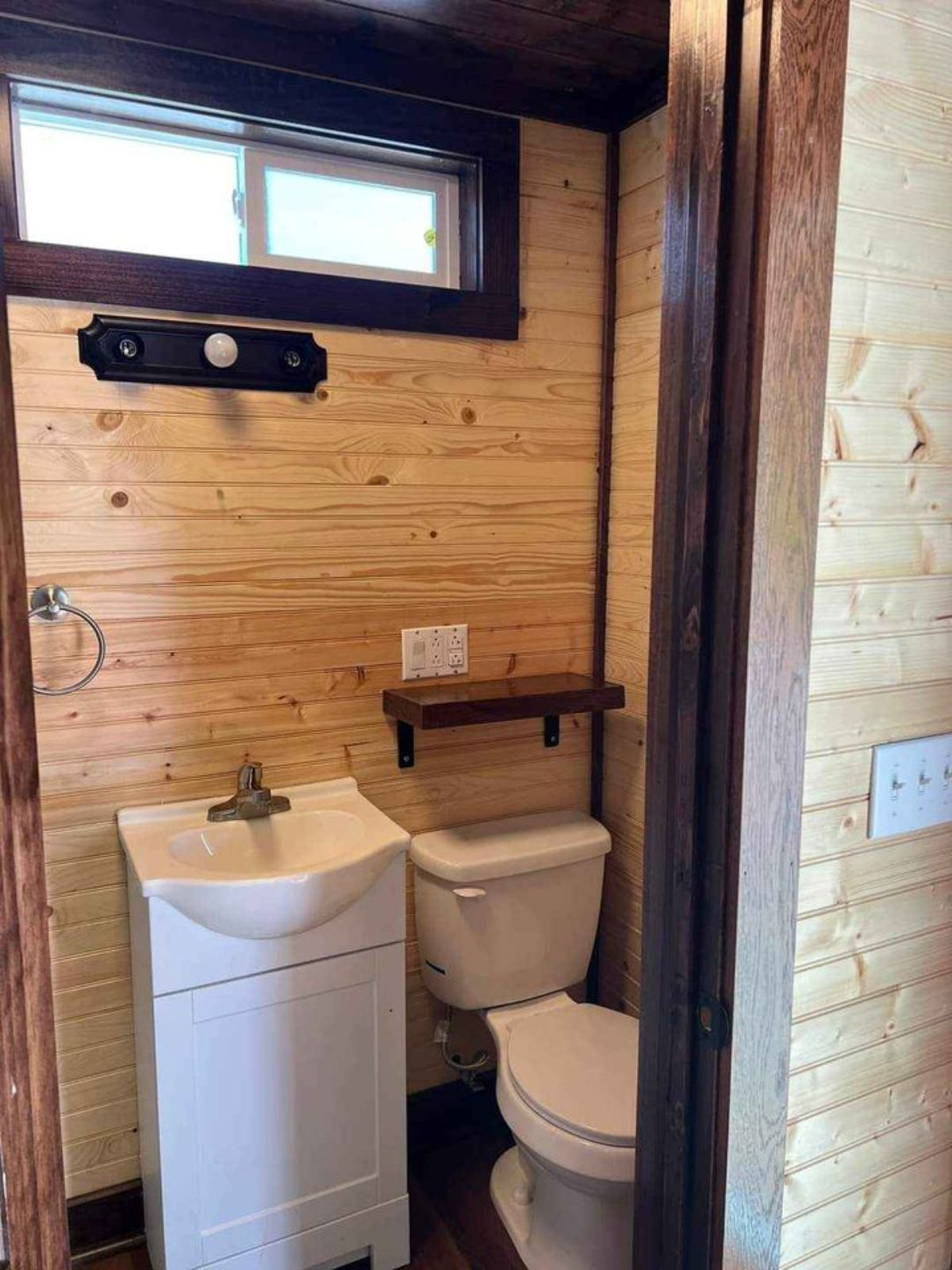 Bathroom of Spacious Tiny House has a standard toilet and sink with vanity and mirror