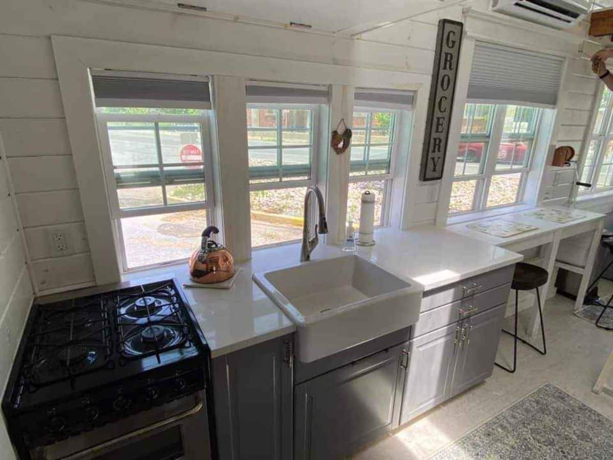 Kitchen area of 24’ Tiny House has a 4 burner stove, a sink and counter top.
