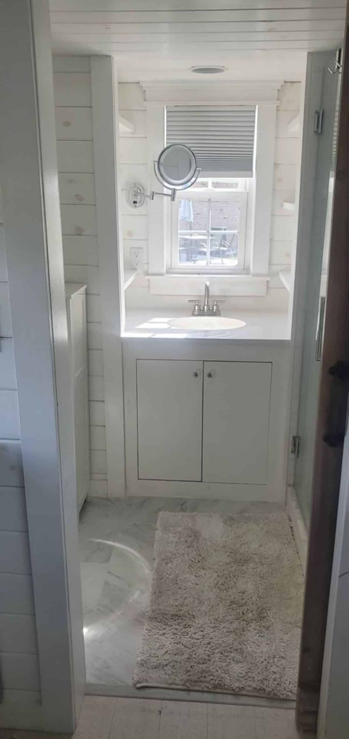 Bathroom of 24’ Tiny House has a sink with vanity and mirror and separate shower area
