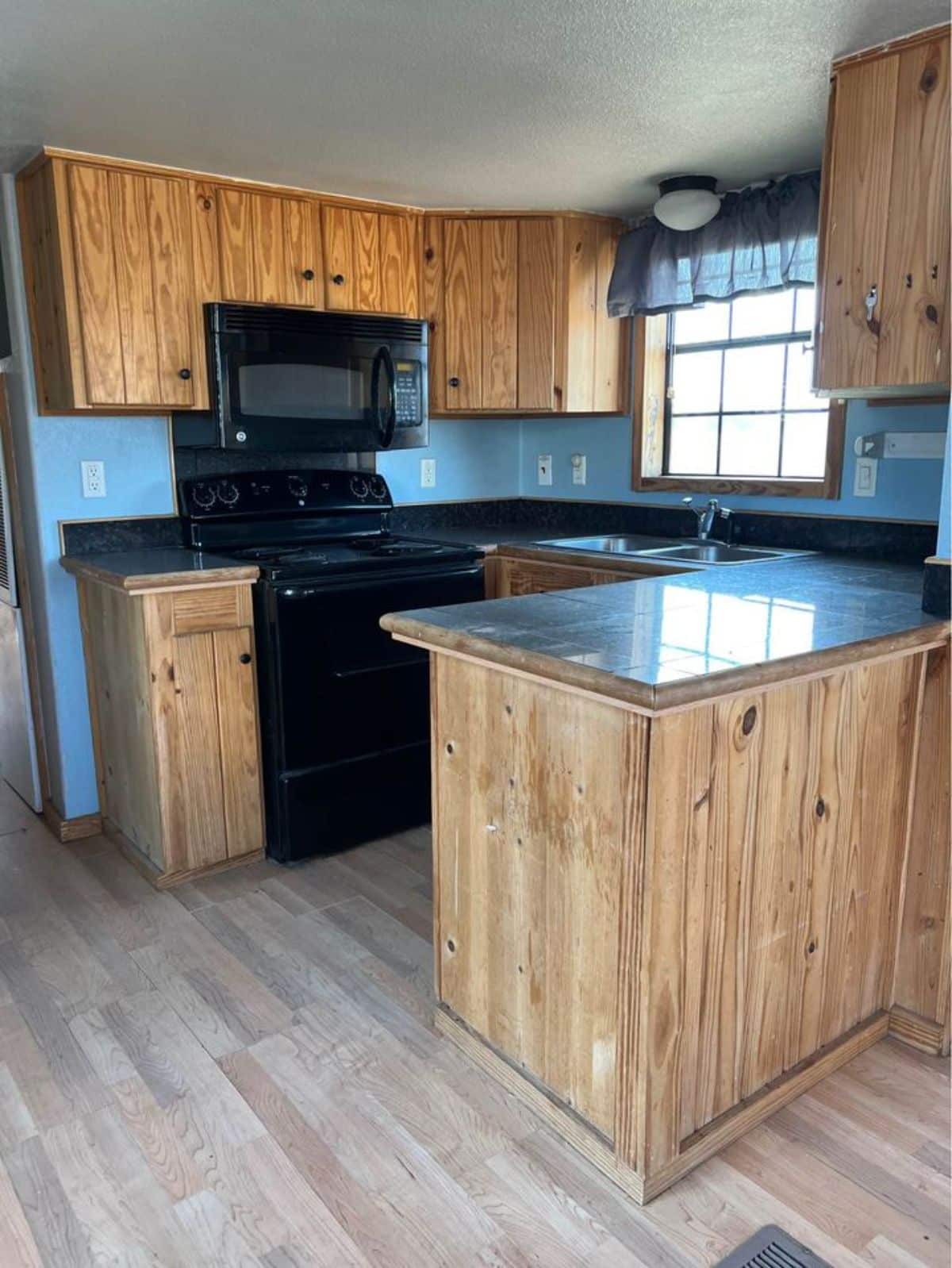Open Kitchen area of 40’ Tiny Home has a oven cum stove, sink, counter top and refrigerator