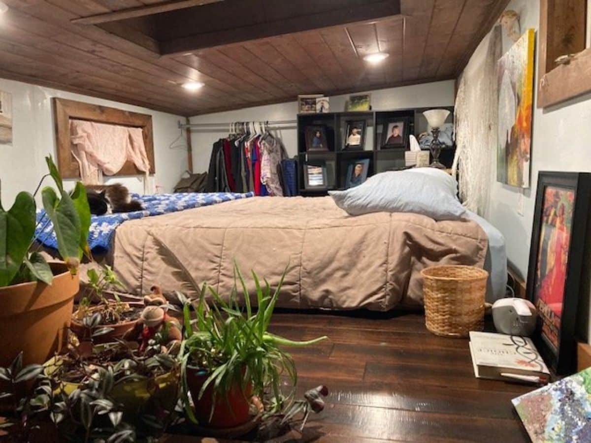 Loft bedroom area of Charming Tiny House has queen mattress, wall mounted storage and still ample space left