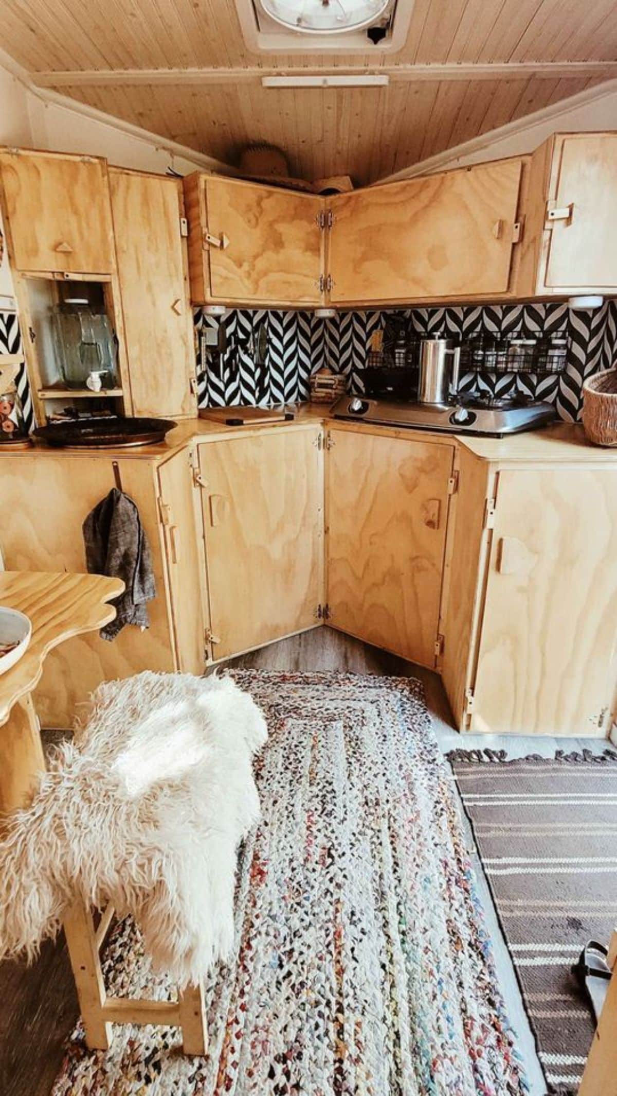 Compact kitchen area of 14’ Tiny Camper has a two burner stove, refrigerator etc