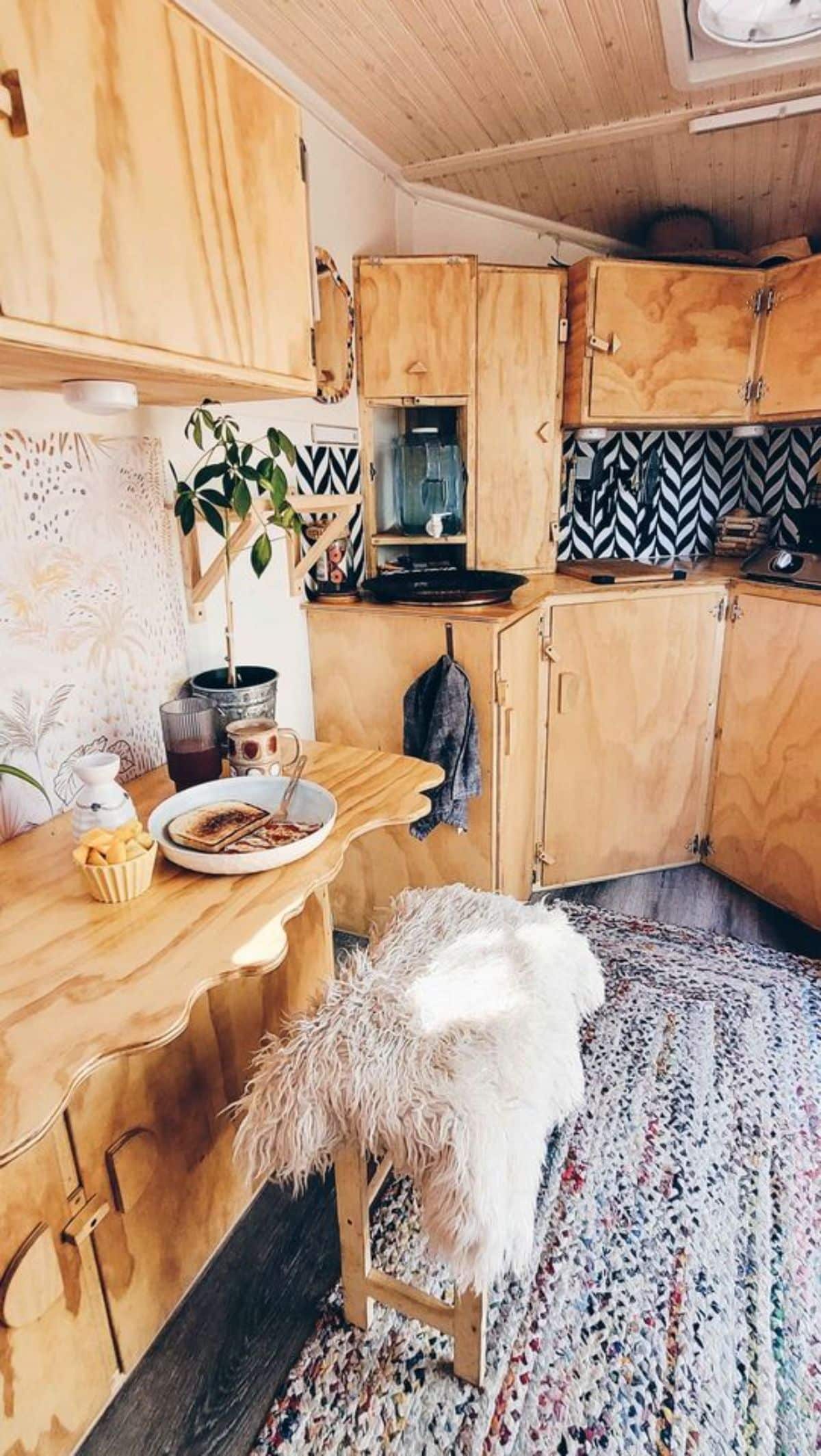 Wooden dinning area and sitting area opposite to the kitchen of 14’ Tiny Camper makes it amazing