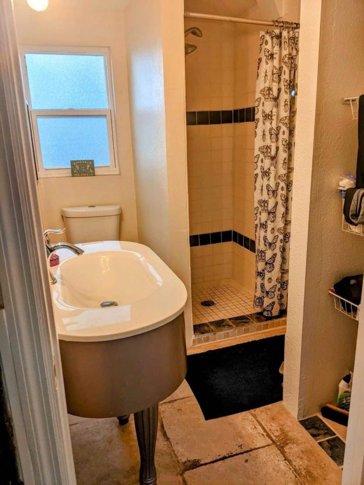 Bathroom has a sink, storage racks and separate shower area