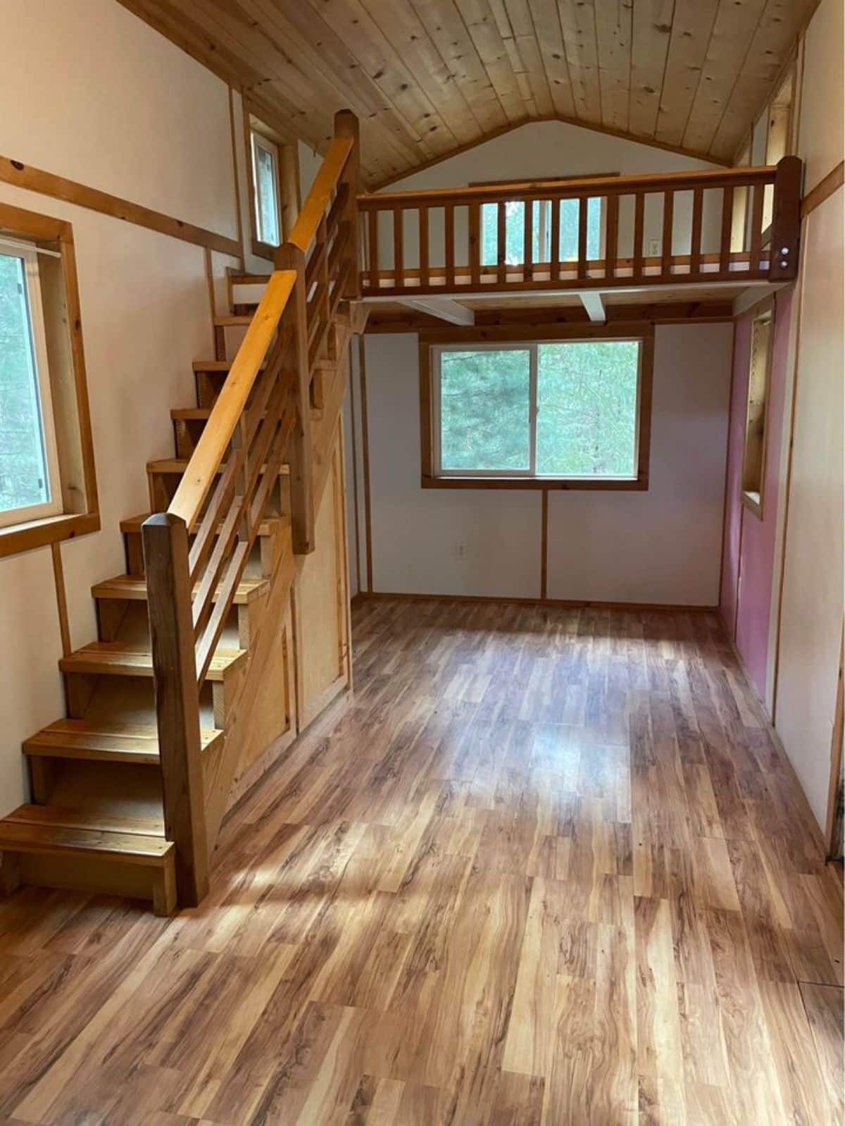 Living area of 27’ Tiny House With Two Lofts is small but brighter because of windows and has a loft above