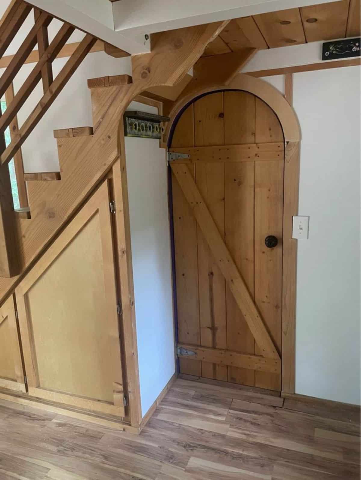Stylish main door of 27’ Tiny House With Two Lofts has storage under the stairs