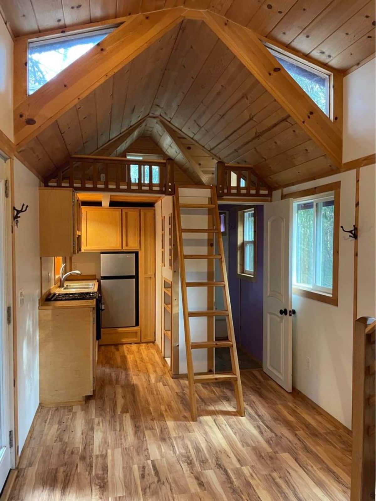 One loft is above the kitchen while another is above the living area of 27’ Tiny House With Two Lofts