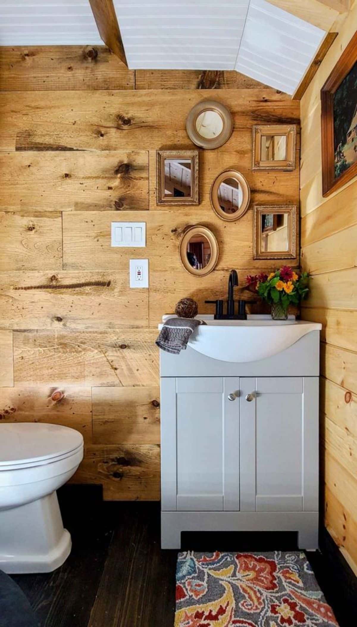 Stunning bathroom of 36’ Fully Furnished Log Cabin has a sink with vanity and mirror