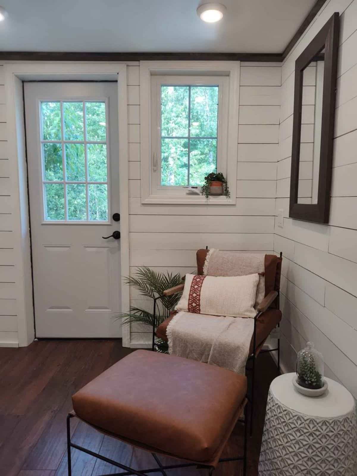 Living area of 38’ Tiny House has a chair, a futon and a side table