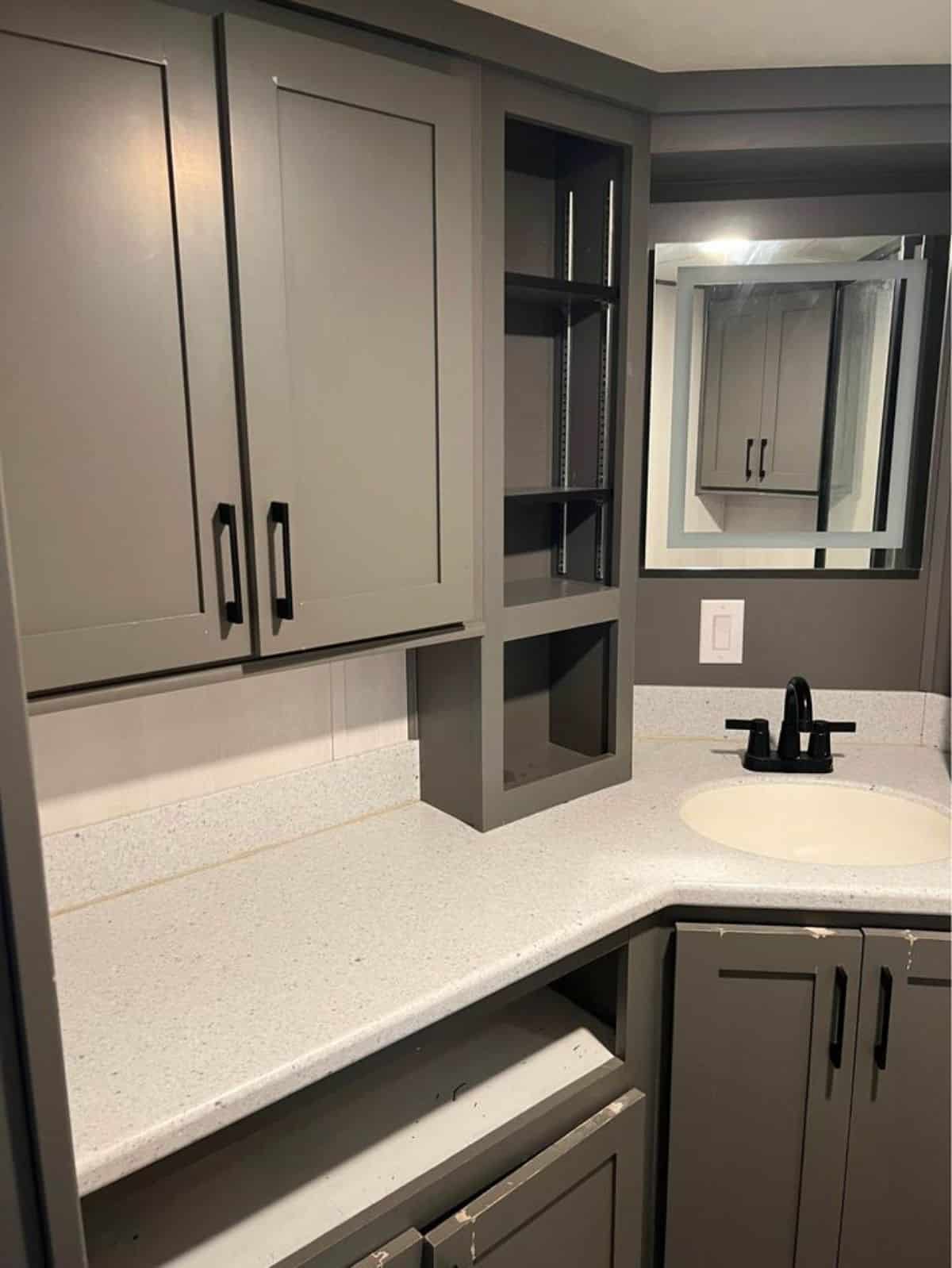 Sink with vanity and mirror with lost of storage cabinets in bathroom of 399 sf Park Model Tiny House
