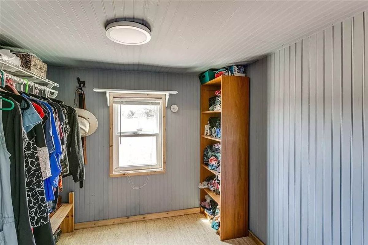 Walk in dressing room and closet of Adorable Tiny House with Land has led lights