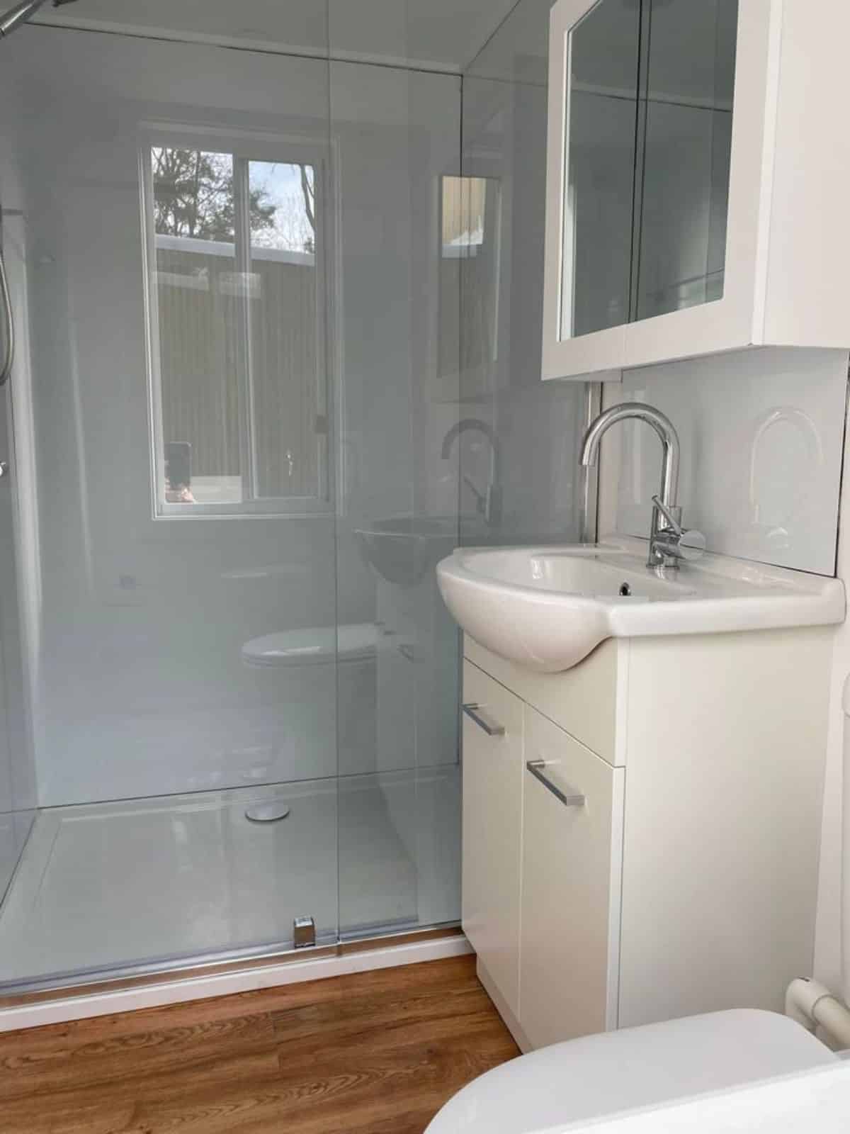 Sink with vanity and mirror and separate shower area in bathroom of Modern Two Storey Tiny Home
