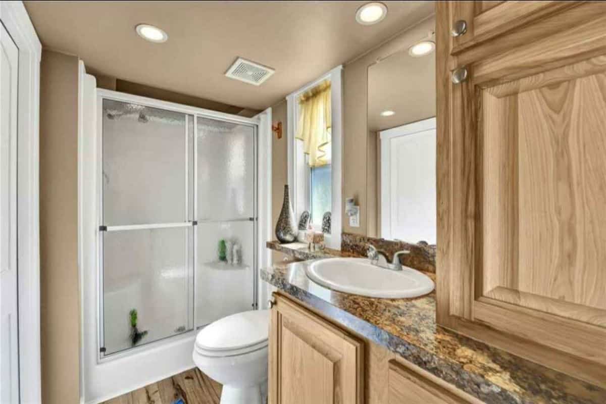 Bathroom of Spacious 3 Bedroom Tiny House has a sink with vanity, standard toilet and separate shower area