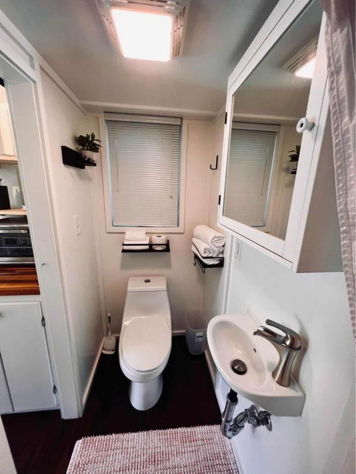 Bathroom of 20’ Furnished Tiny Home has a standard toilet, sink with mirror