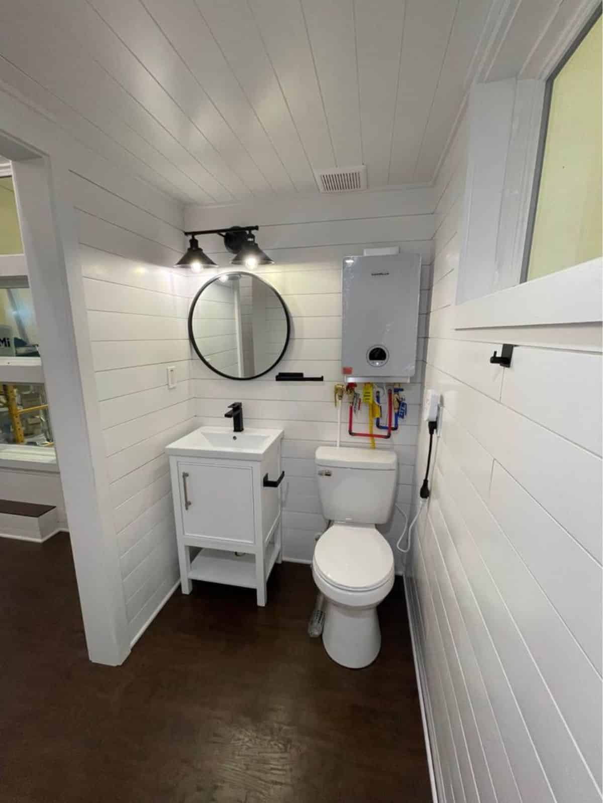 Bathroom of 20' Modern Tiny Home has a standard toilet, sink with vanity and mirror