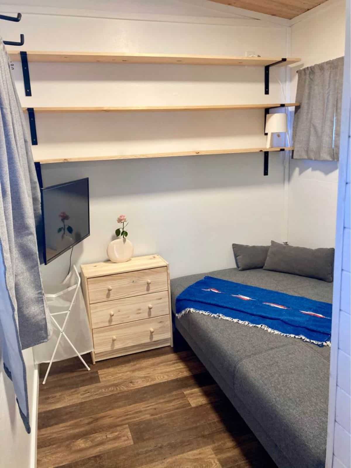 Living cum bedroom has a small bed, television set, side drawers and storage cabinets