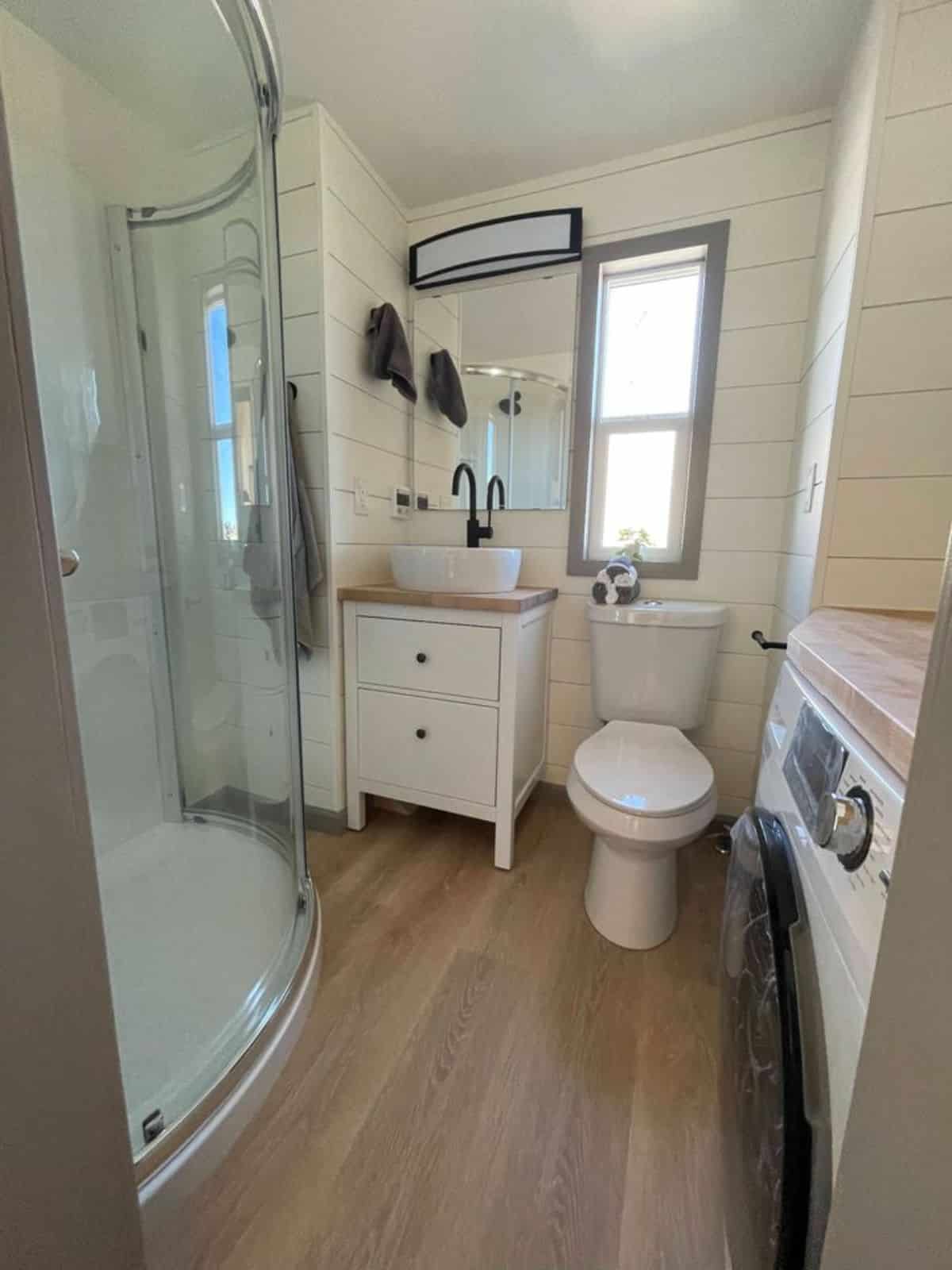 Sink with vanity & mirror, standard toilet and separate shower area