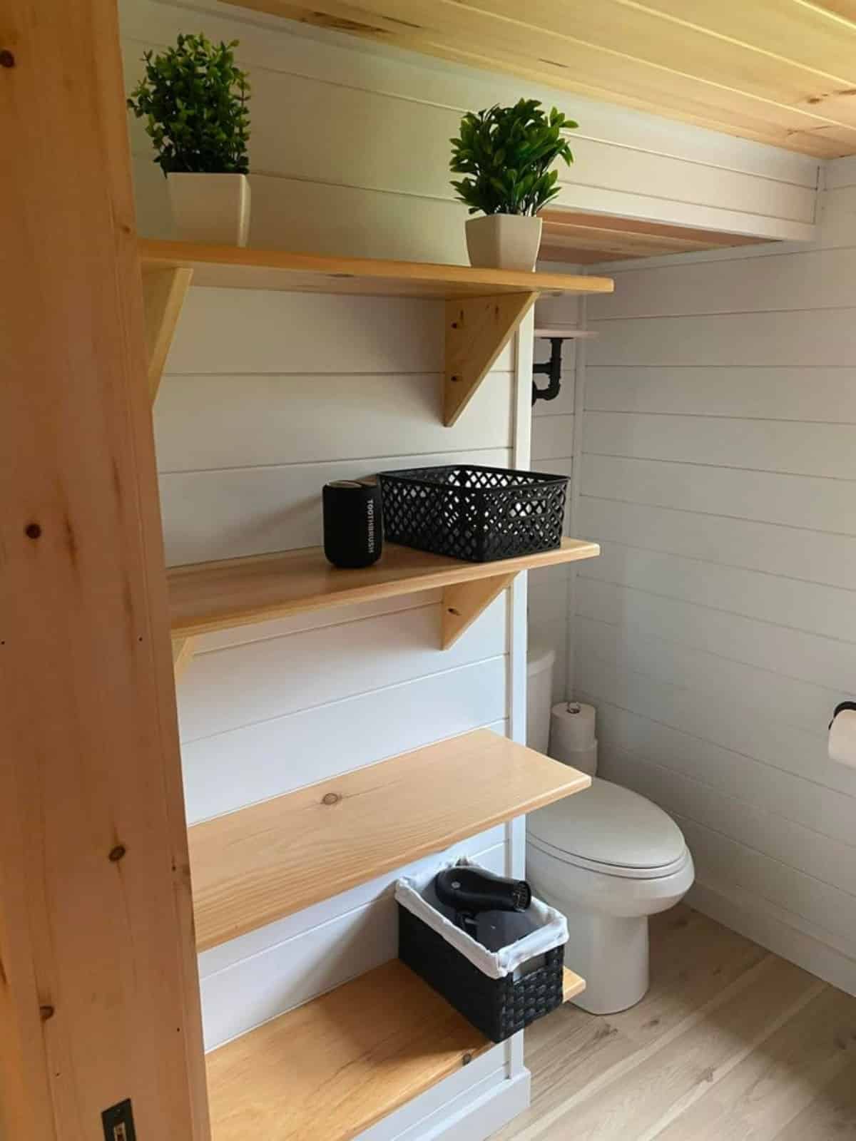 Standard toilet and Stylish wooden racks installed in bathroom of 30' Custom Hickory Lodge is the Tiny Cabin