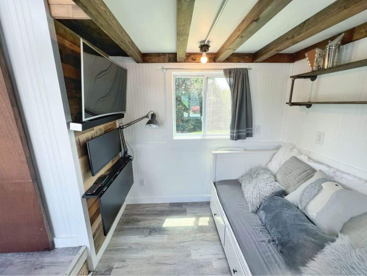 Living area of 325 sf Tiny Farmhouse has a couch, wall mounted television set