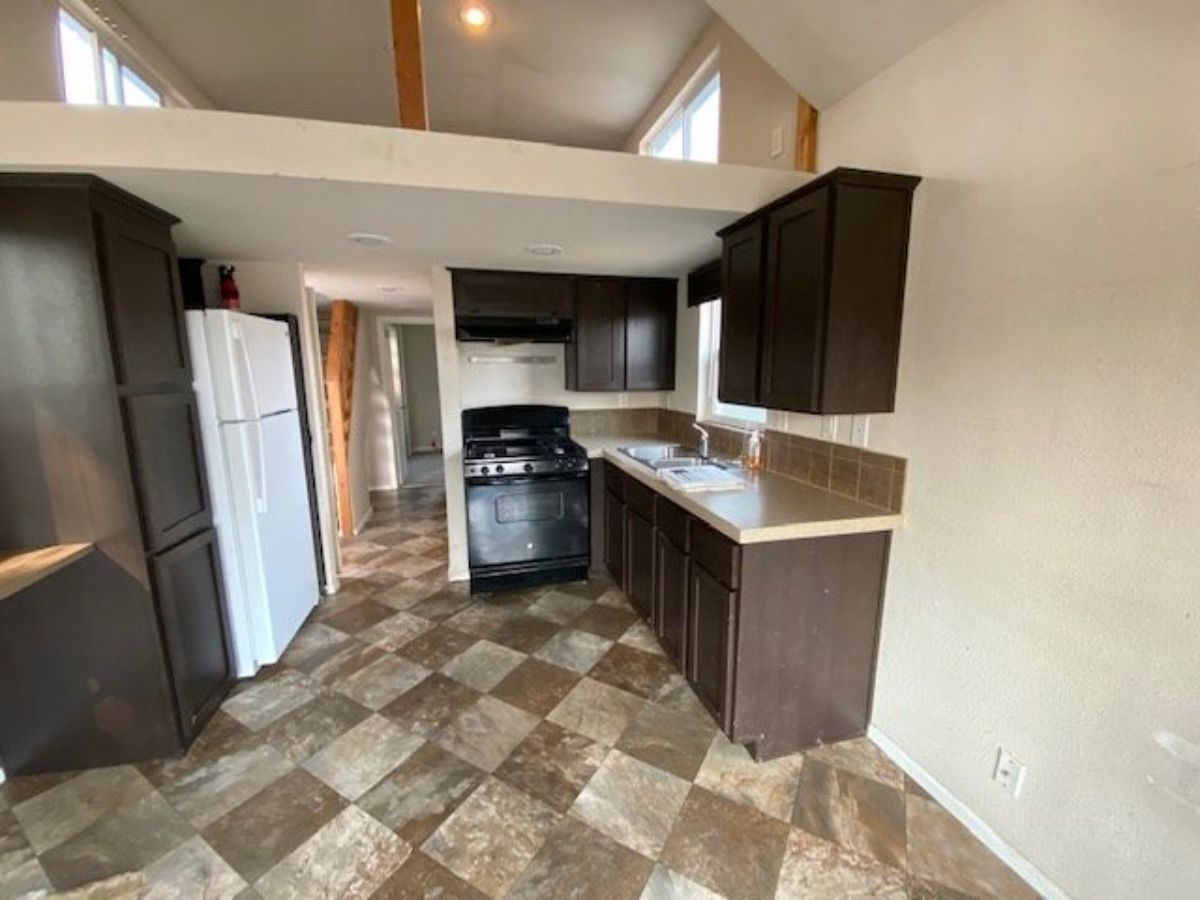 Kitchen has a counter top, propane gas burner and oven with refrigerator and lots of storage cabinets