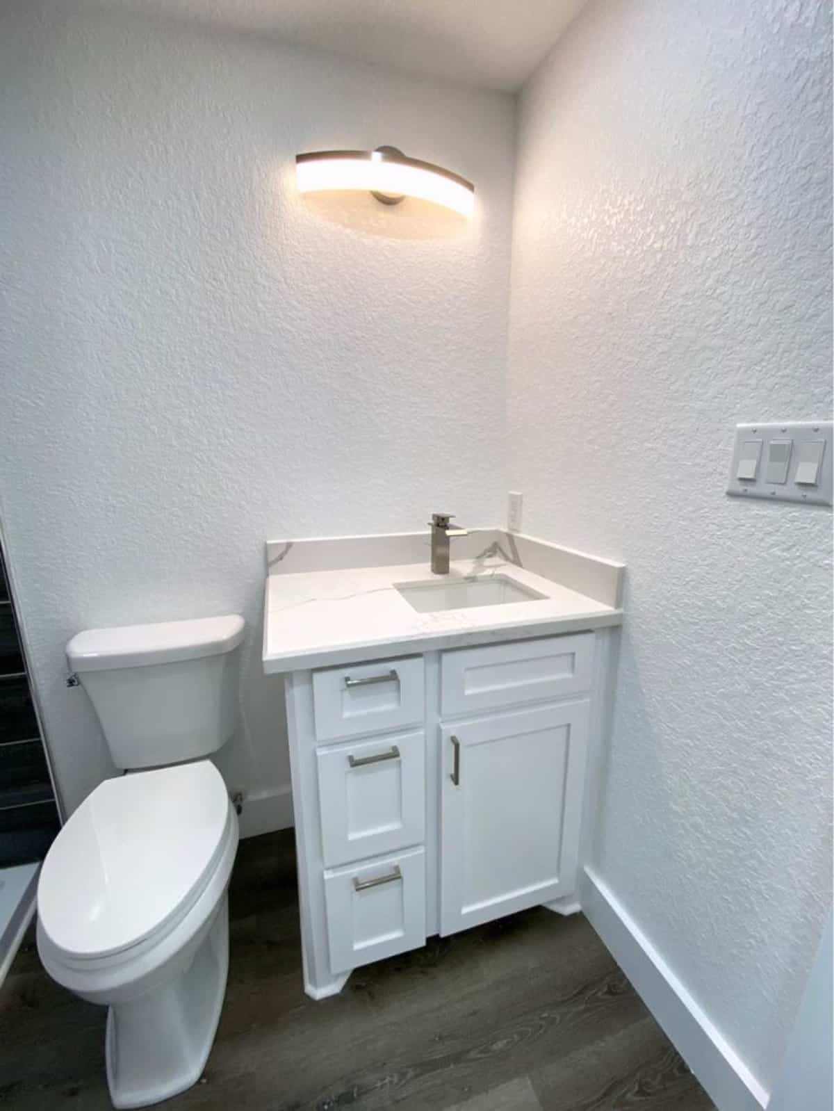 Stunning white bathroom has a sink with vanity and standard toilet