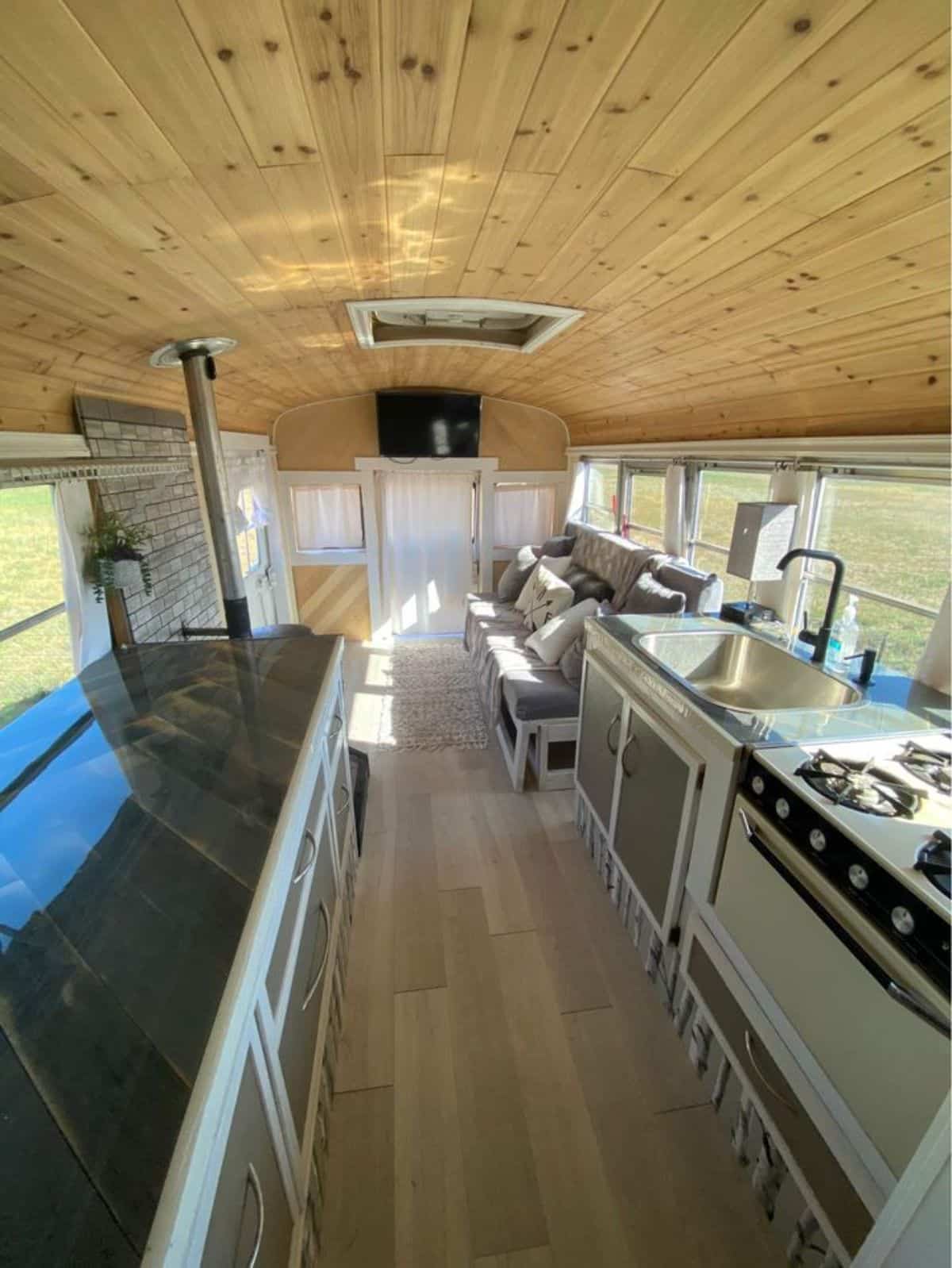 Classy wooden interior of 40' Skoolie Tiny House on wheels from bedroom view