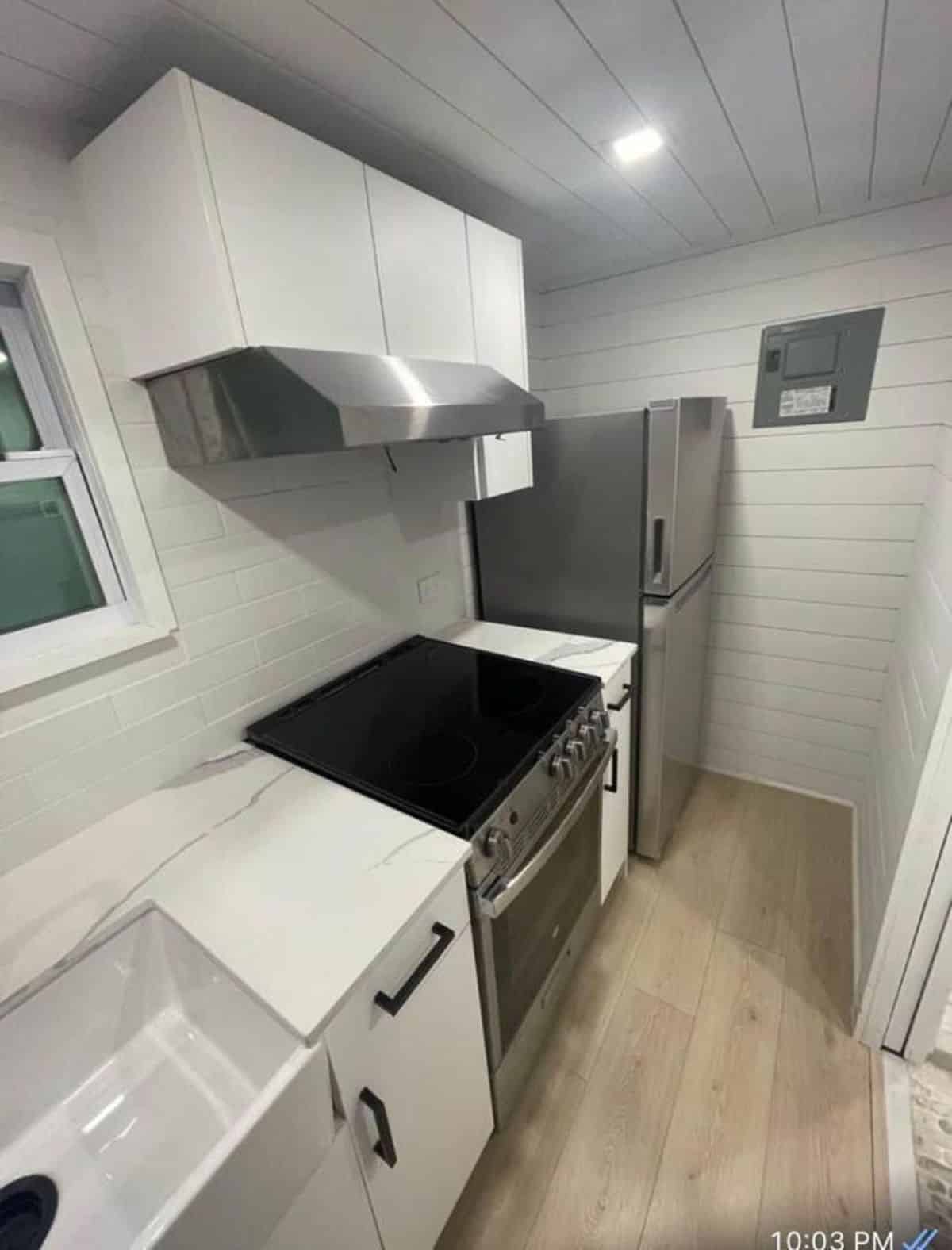 Kitchen area of Luxurious Tiny Home has a stove, oven, refrigerator and chimney