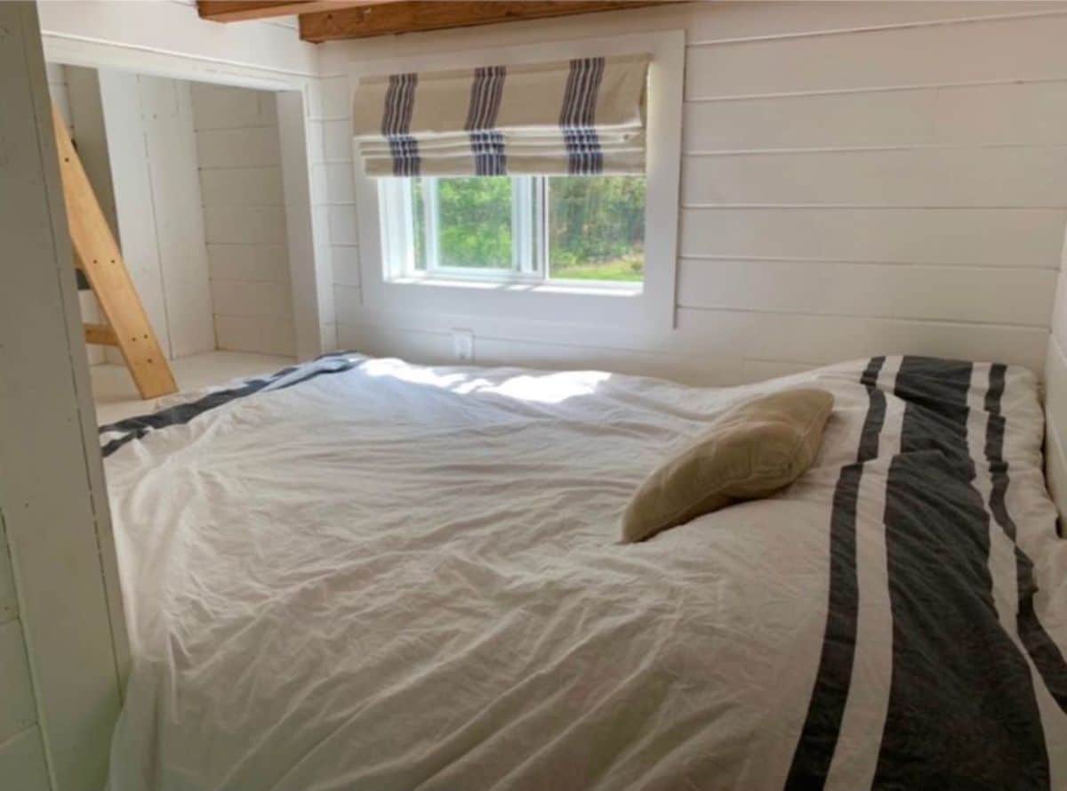 Main floor bedroom has a comfortable queen bed with large windows and a ladder to the loft bedroom