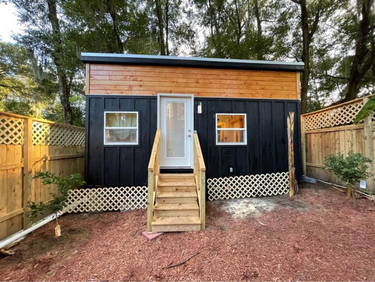 Unique color combination of black with tones of wood strangely blends well together at main entrance view of Towable tiny house