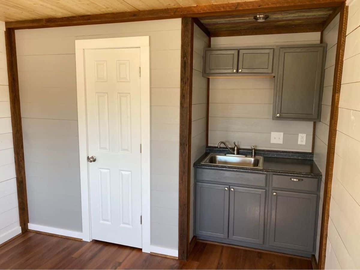 Small kitchen area and a door to bathroom of 24' Cabin Tiny House