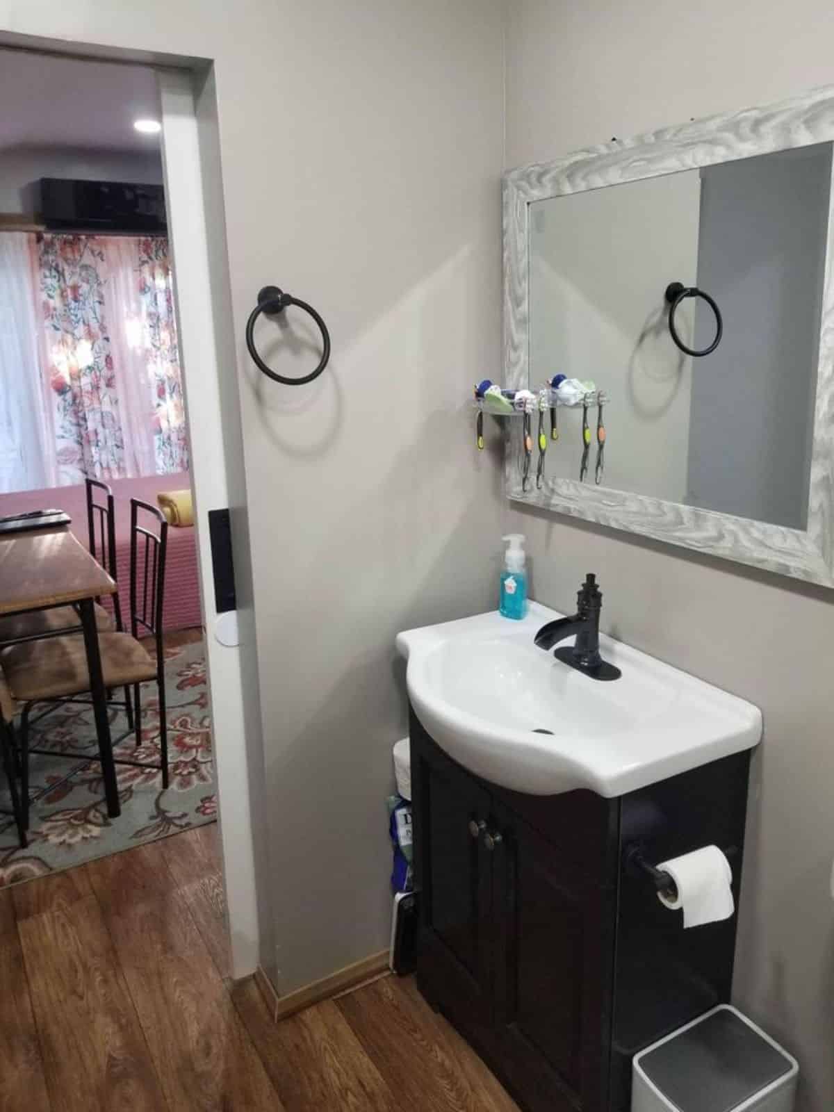 Bathroom area has a sink with vanity & mirror and standard toilet