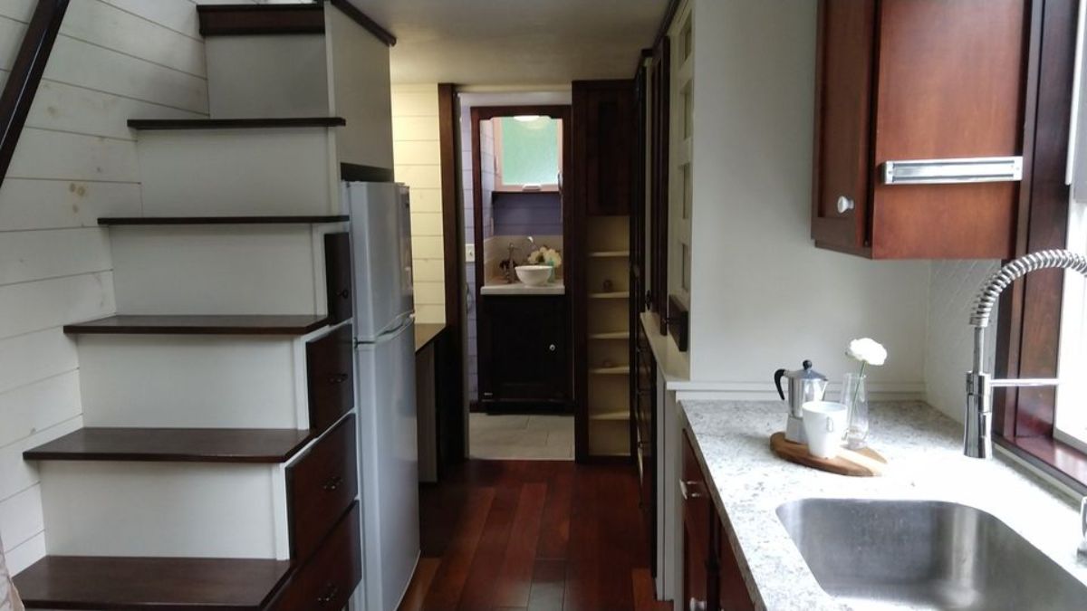 Stairs with storage cabinets and refrigerator in underneath storage leads to the main bedroom