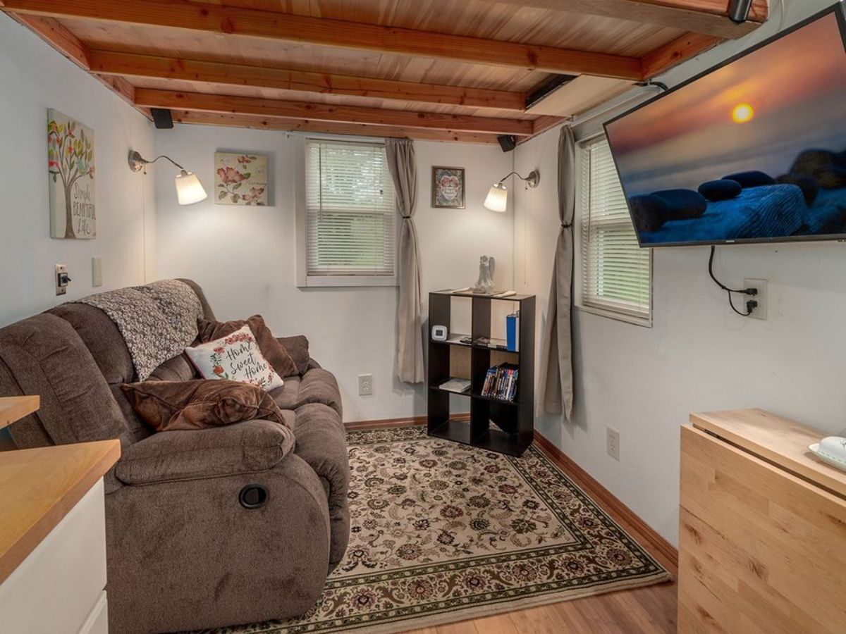 Living area of 29' Custom Tiny House has a comfortable couch, book standa and wall mounted television set