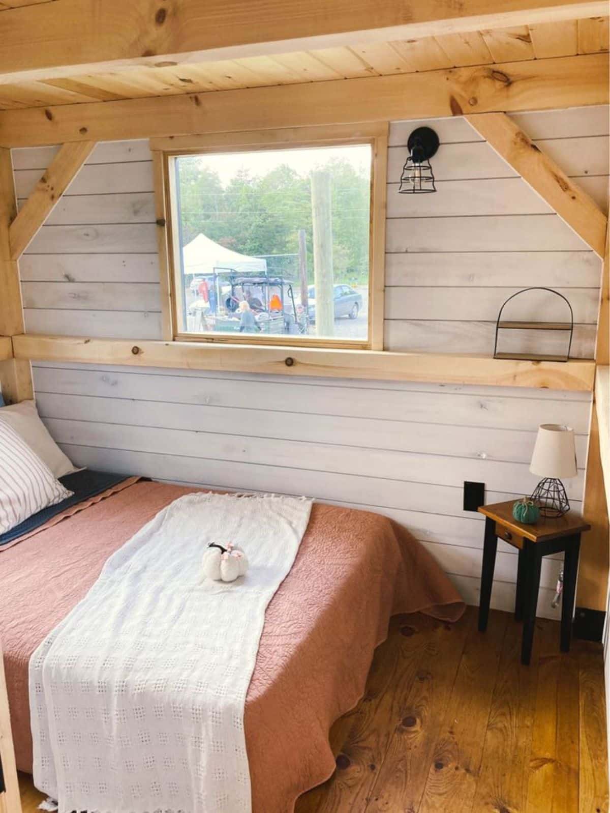 Main floor bedroom of 30' Delightful Tiny House has a bed, side table, lamp but can be converted to designated living area also