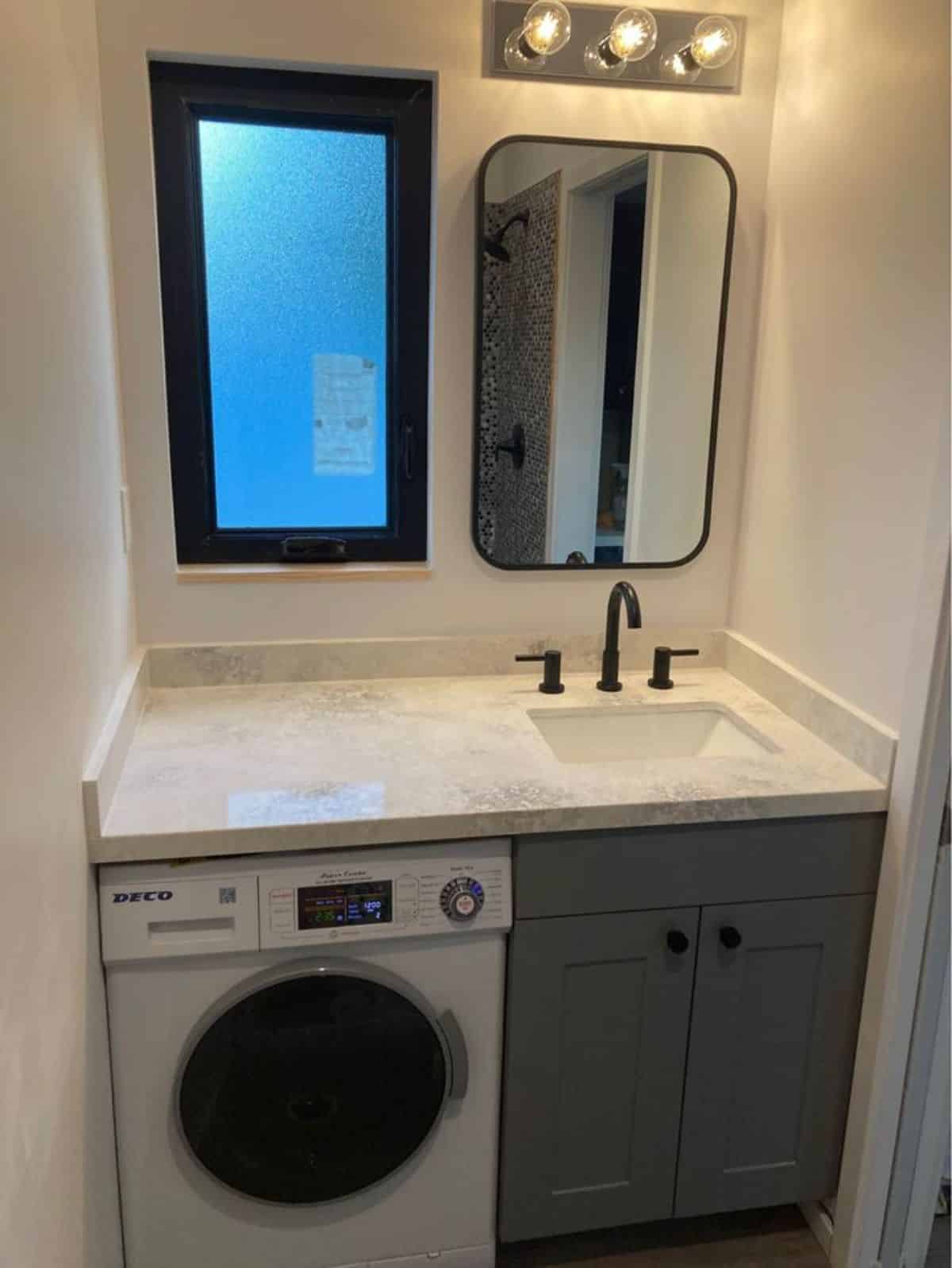 Well designed bathroom has sink with vanity & mirror and washer dryer combo