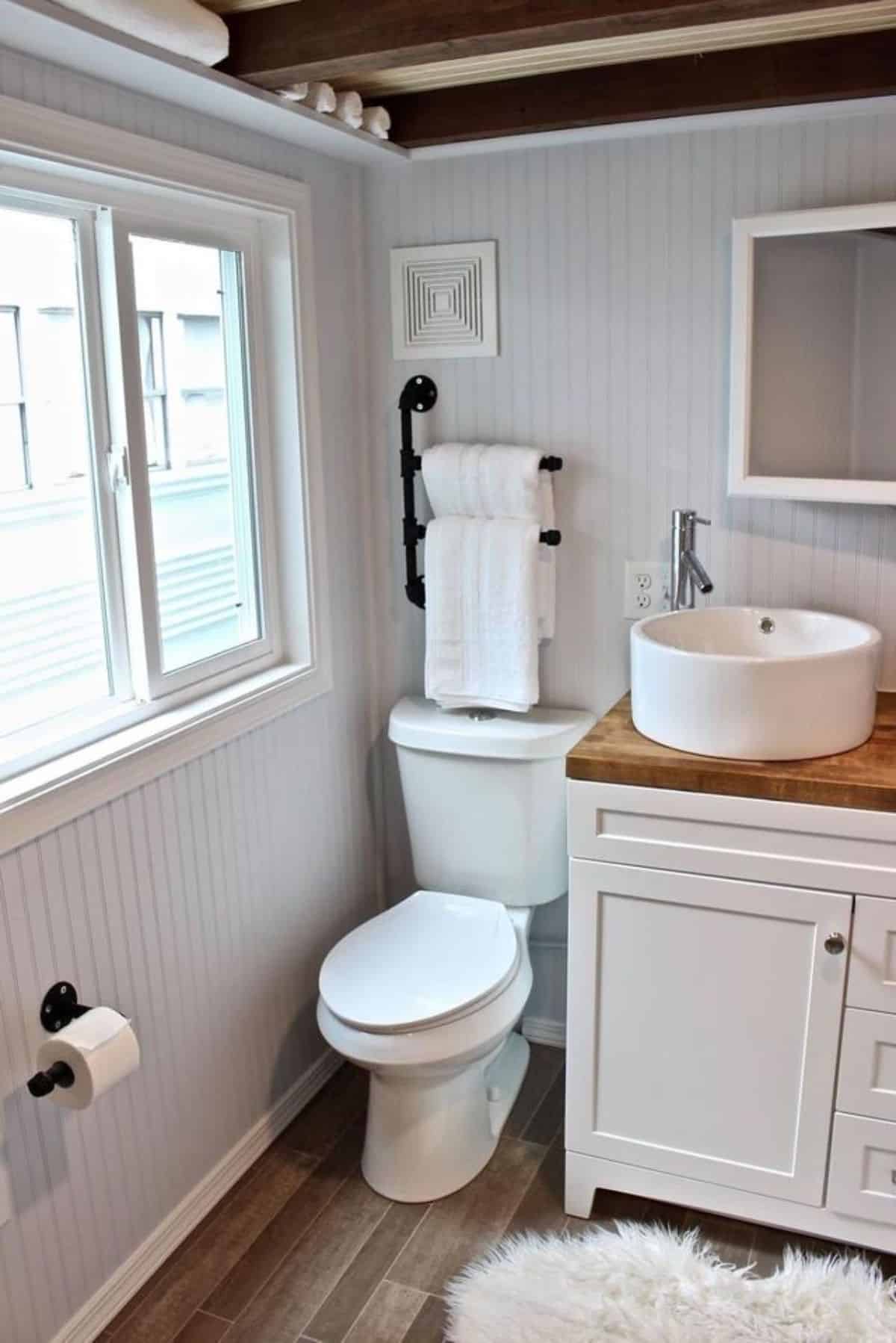 Standard toilet, sink with vanity & mirror in bathroom of Certified Durable Tiny Home
