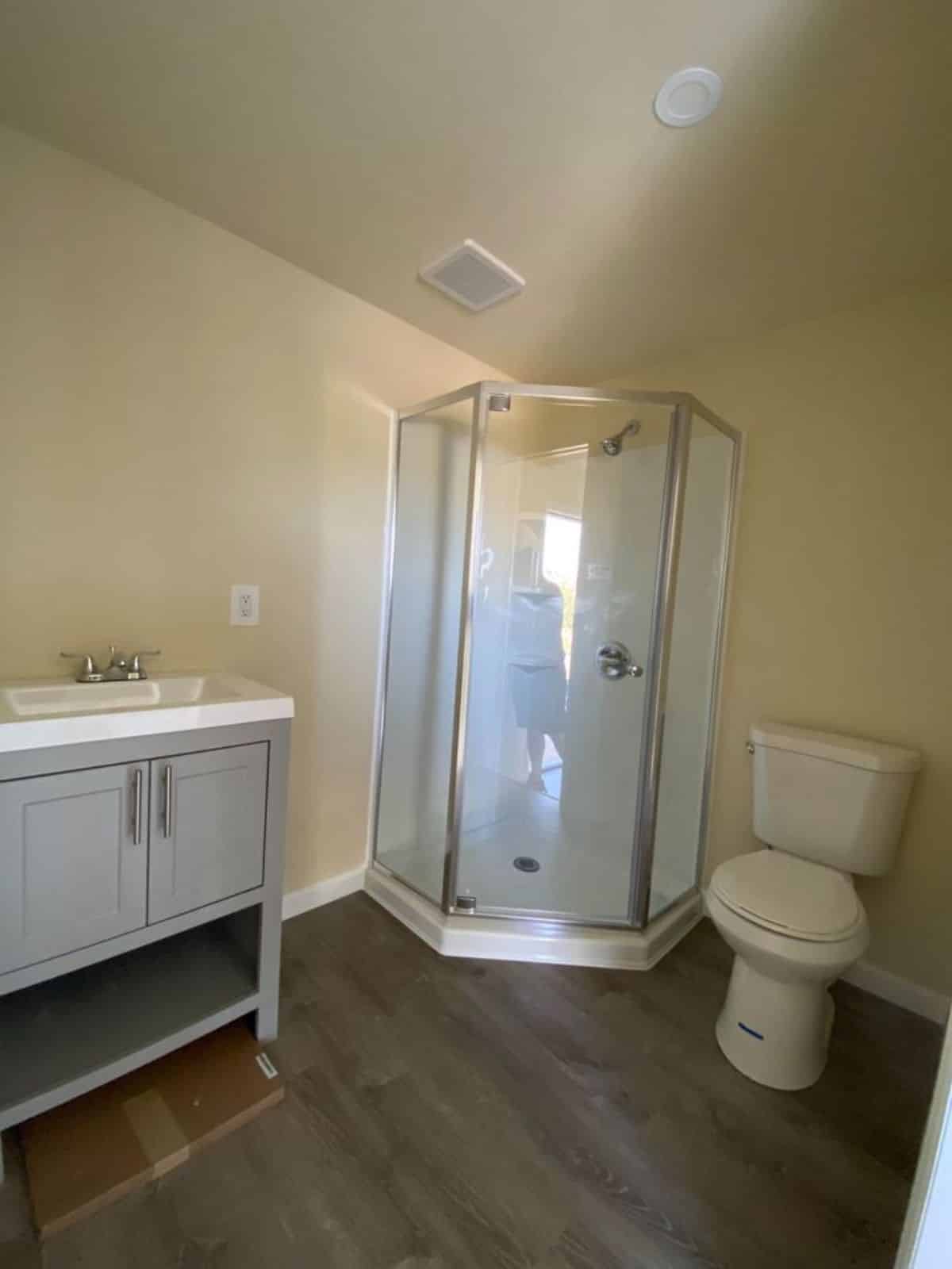 Bathroom is spacious with standard toilet, sink with vanity and separate shower area with glass door