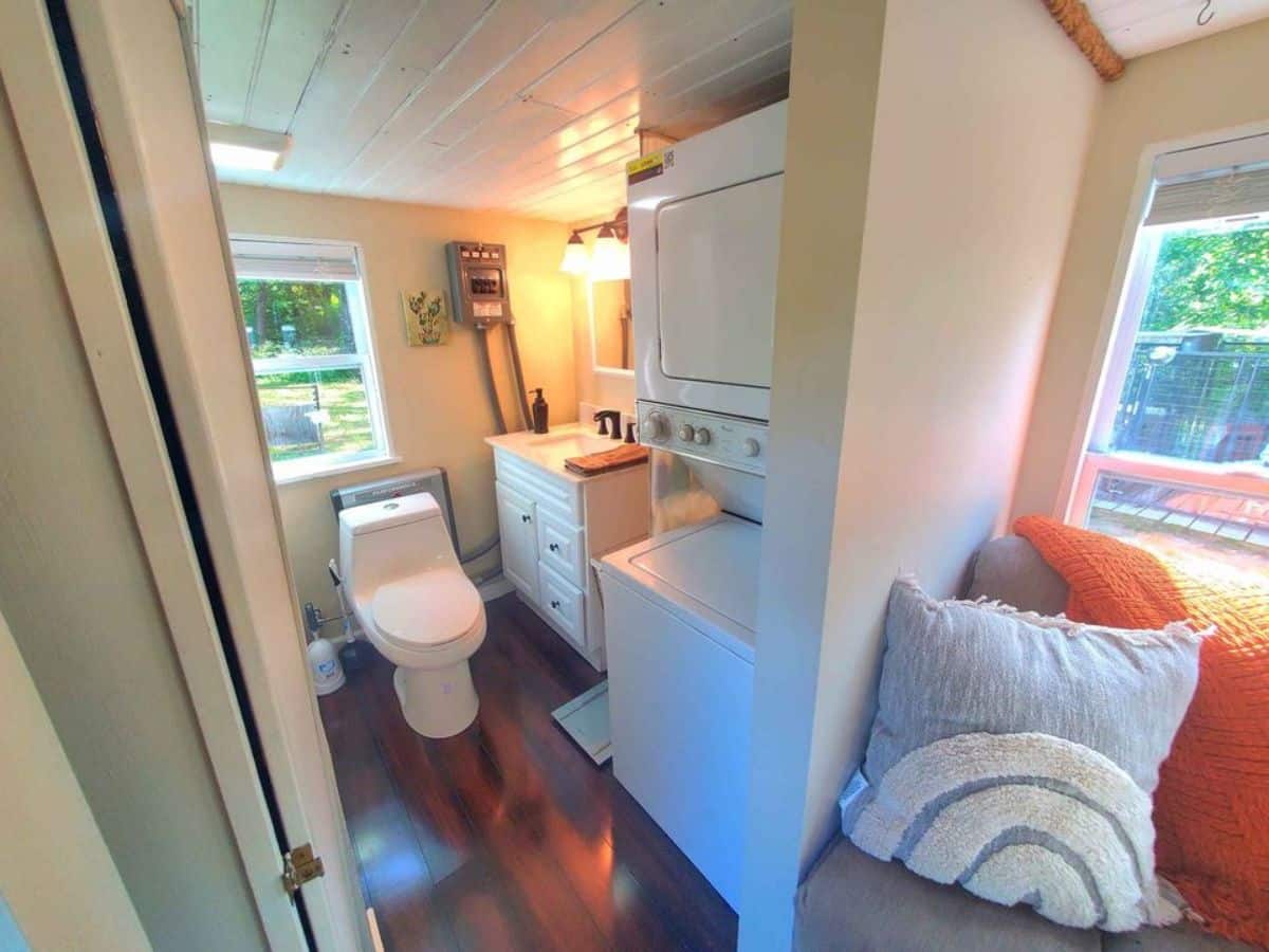 Bathroom of Move-In Ready Tiny Home has a standard toilet, washer dryer combo and sink with vanity & mirror