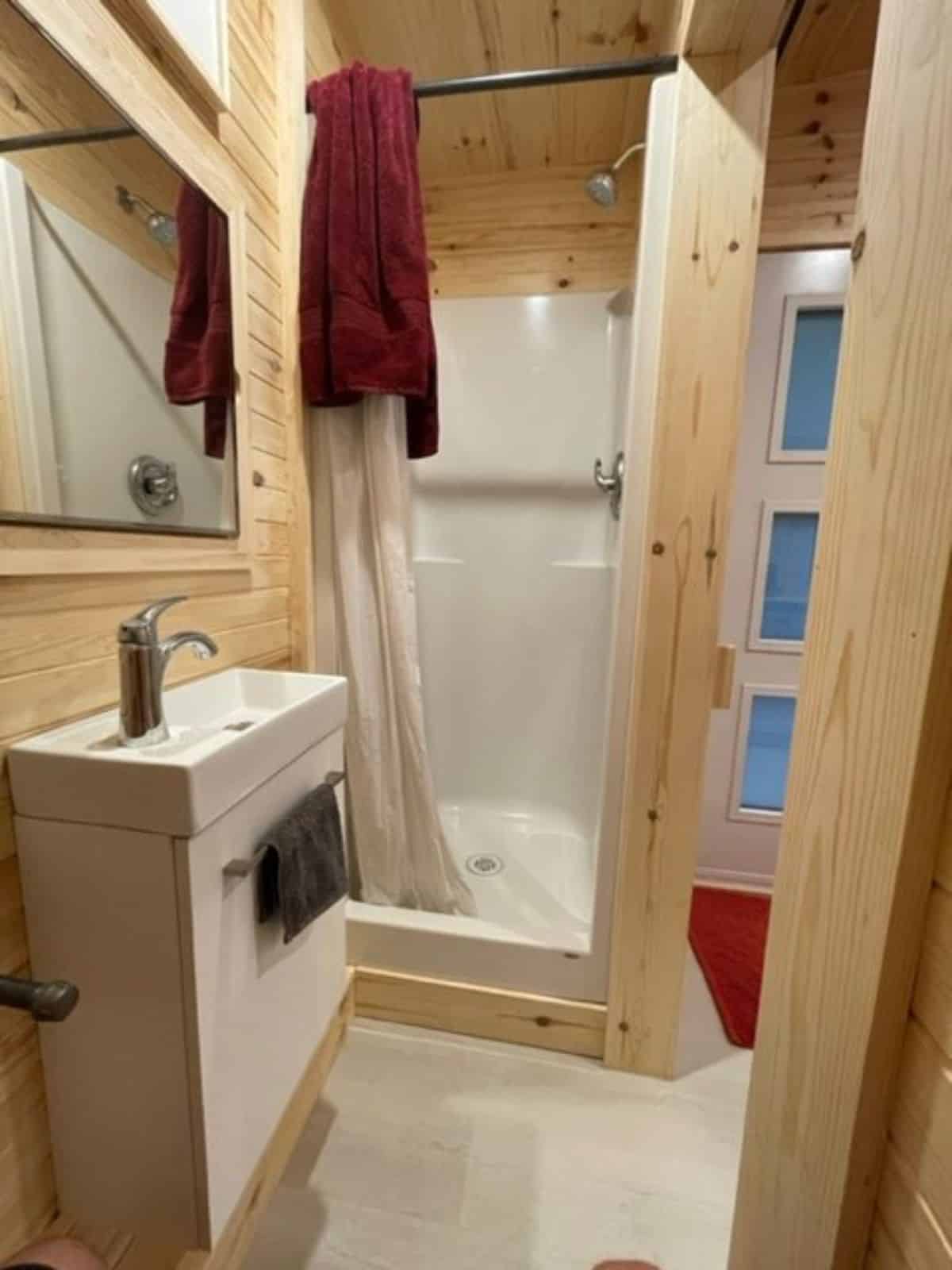 Bathroom of This Elegant Tiny Home  has a sink with vanity & mirror, separate shower area and standard toilet