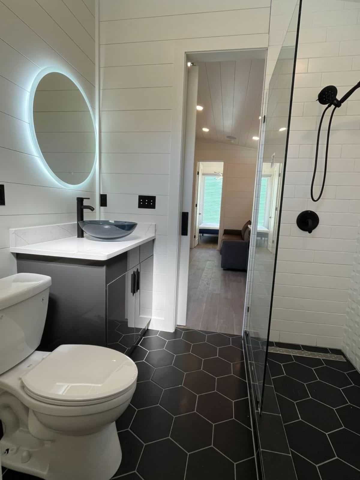 Bathroom is on another level with beautiful floor and walls with standard toilet and sink with vanity & shinning mirror