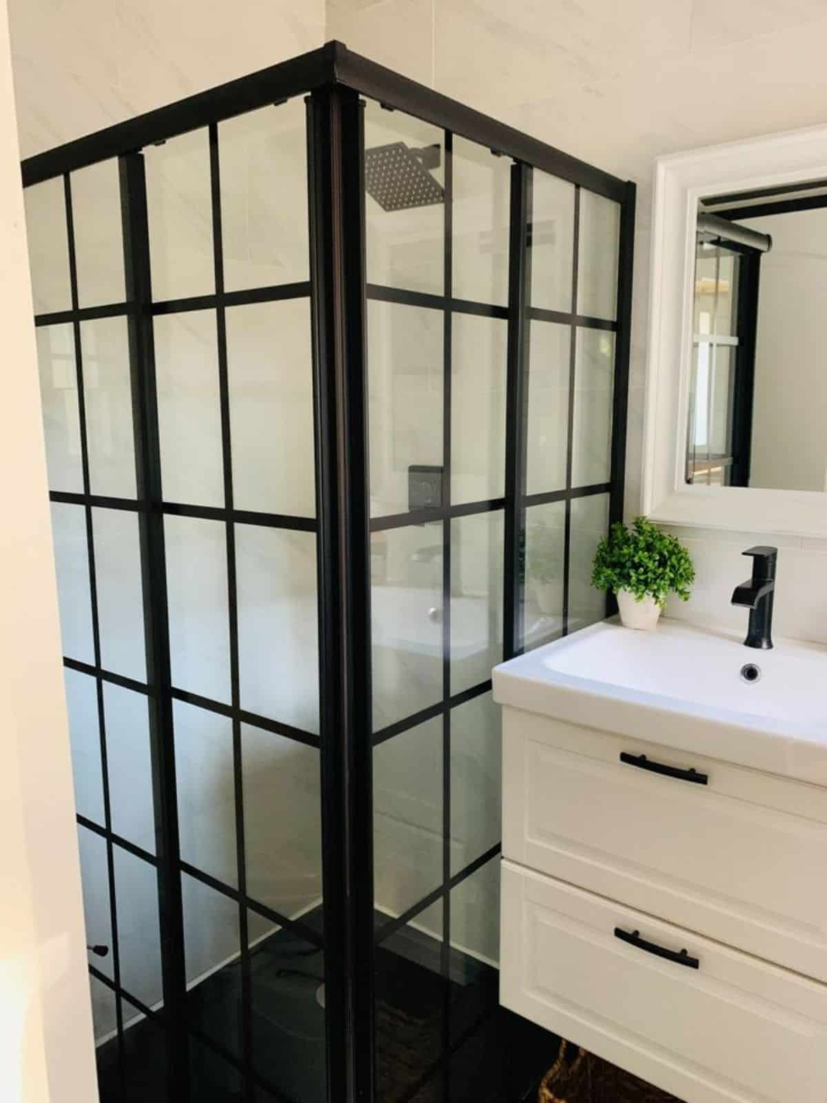 Separate shower cube with standard toilet and sink with vanity & mirror in bathroom of 20'  Shipping Container Tiny House