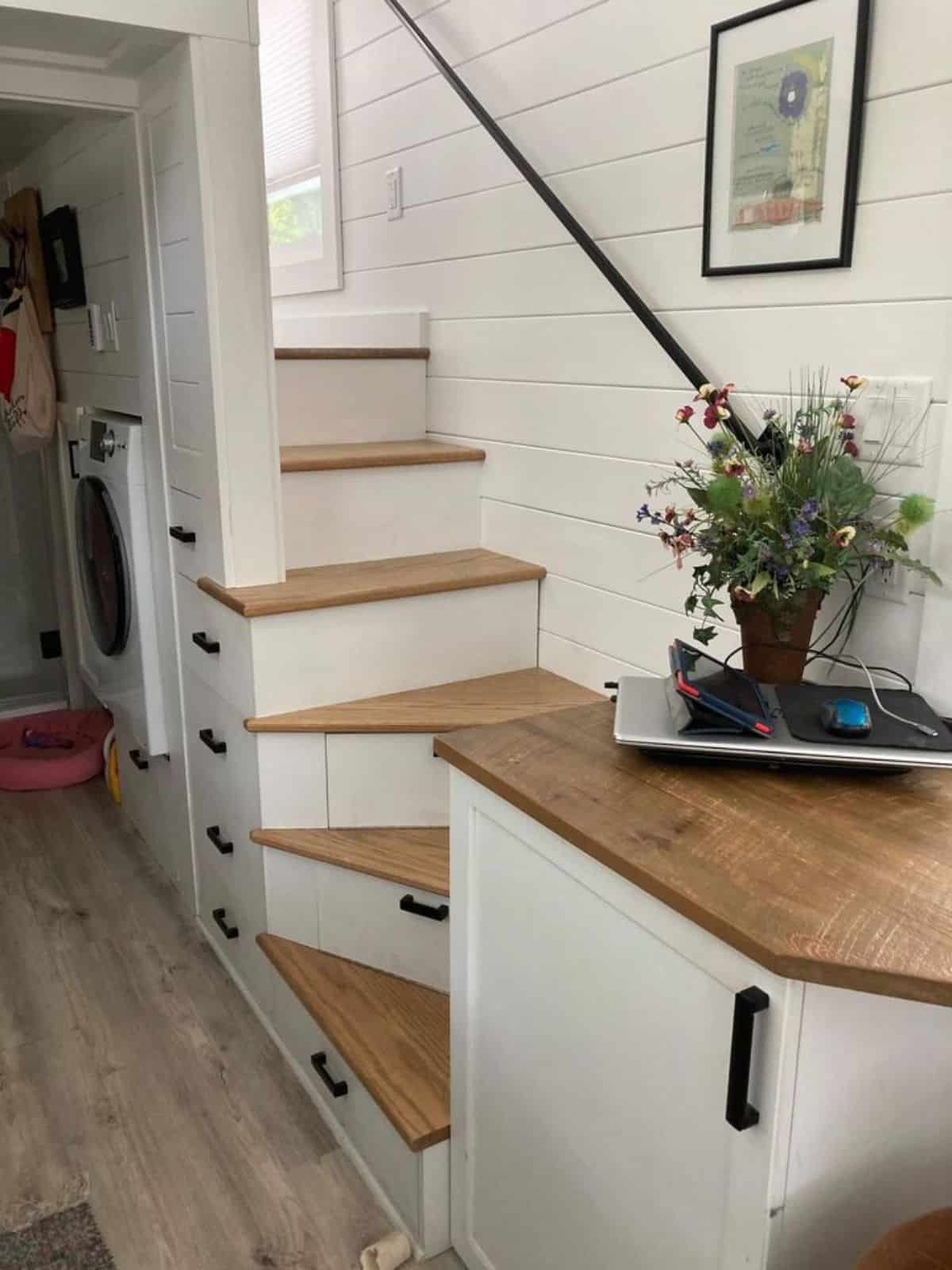Stairs leading to bedroom has washer dryer combo and other storage underneath