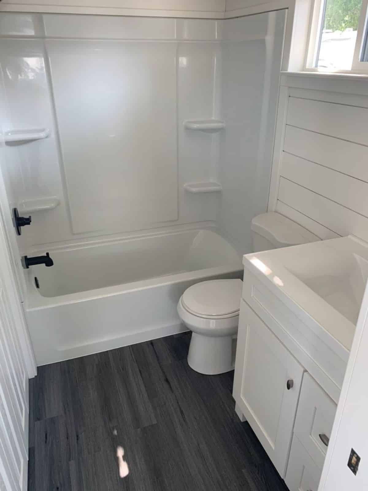 Bathroom of 28' Tiny House has a standard toilet, sink and highlighted point is the bath tub