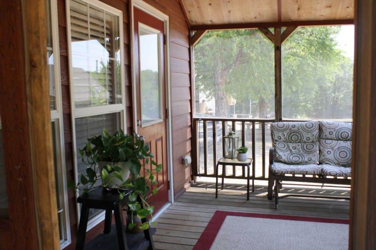 Small porch outside the main entrance has side table and sitting area
