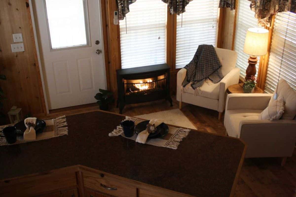 Living area has a sofa chairs, fireplace and side table with lamp