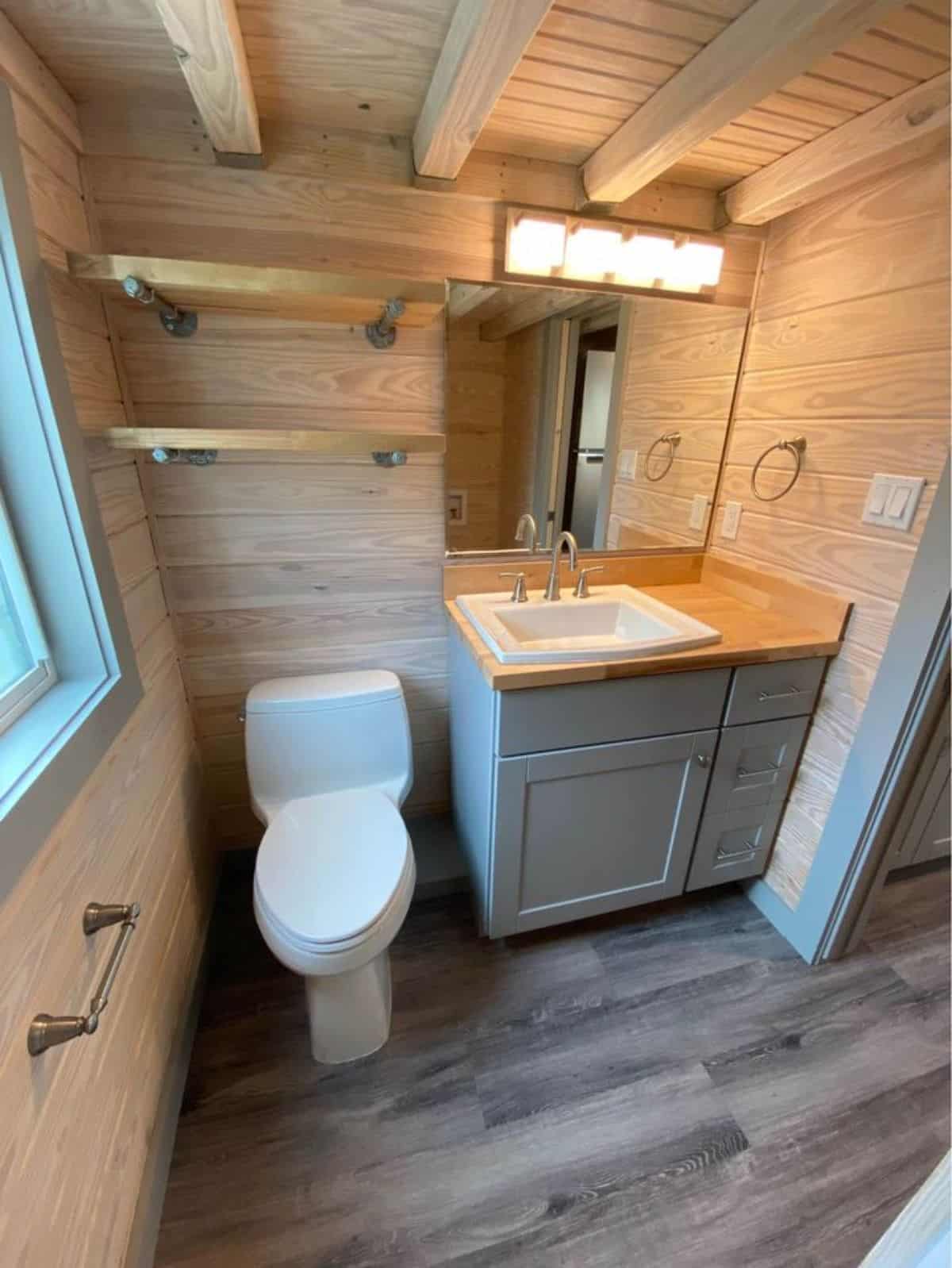 Well styled bathroom has a toilet, sink with vanity & mirror