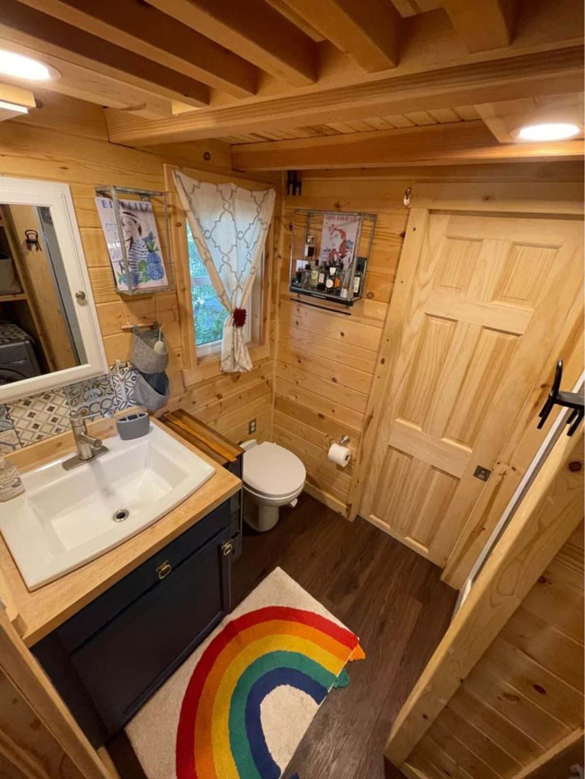Standard toilet and sink with vanity & mirror in bathroom of Lakefront Tiny House
