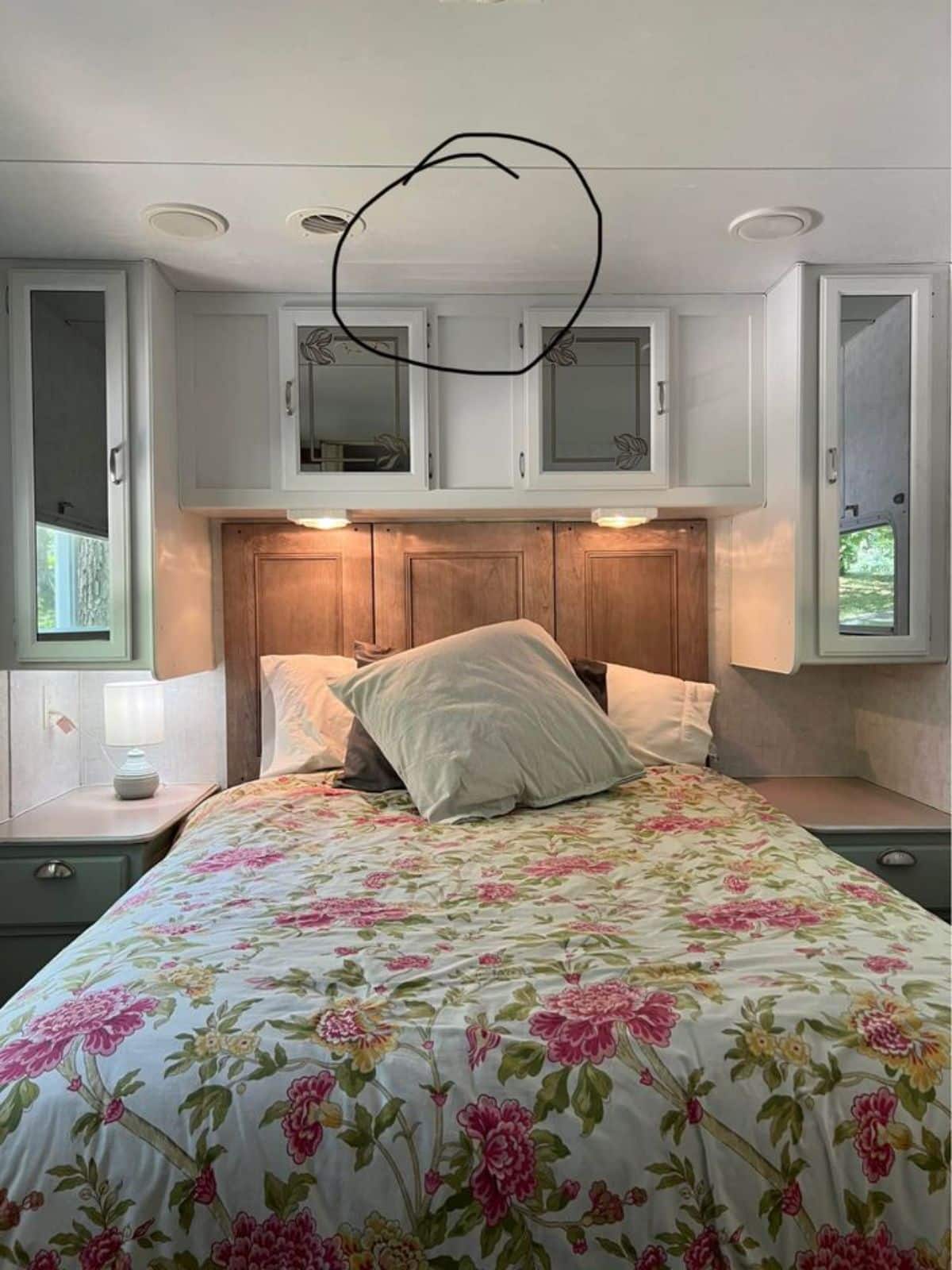 Bedroom of Remodeled Tiny House has a cozy bed and storage cabinets with side tables